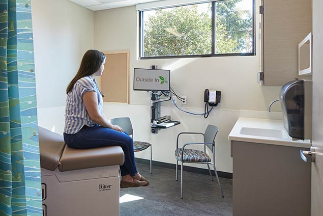 Woman sitting on exam bed in patient room