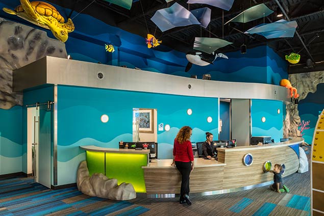 Woman and child standing at aquatic themed check-in desk and lobby