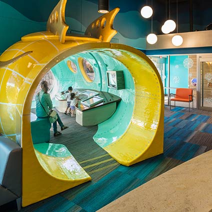 Woman and two children sitting inside interactive display in waiting room