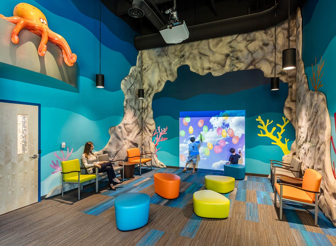 Woman and two children sitting inside interactive display wall in waiting room