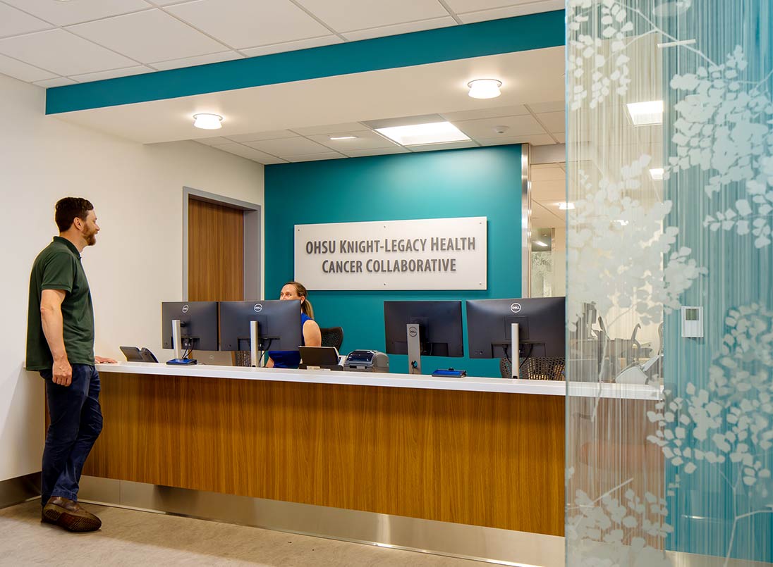 Man checking in at front desk. Woman sitting behind computer